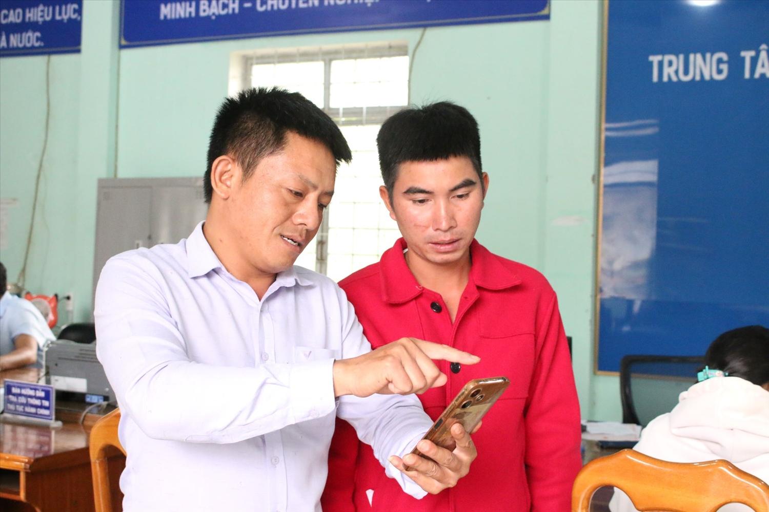 Cán bộ Trung tâm Phục vụ hành chính công xã Ngọk Réo hướng dẫn người dân cập nhật thông tin trên ứng dụng VneID. Ảnh: Ngọc Chí